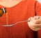 Mother woman pouring liquid medication or antipyretic syrup cough from bottle to spoon