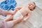 A mother woman puts on a diaper for a baby boy. Mom dresses a happy child in clothes on the bed