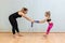 mother yoga instructor and daughter do balance exercises with elastic band