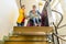 Mother with a young child living with cerebral palsy using electric wheelchair lift to access public building.