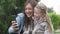 A mother and a young daughter take a selfie on a mobile phone while walking in the park in the summer