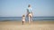 Motherhood. Young mother walks with her little girl to the sea. Blond hair woman holds her daughter hand. Slowly walking