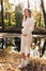 Mothers day. Beautiful young pregnant woman in white tight knit dress with little belly relaxing outdoors by the pond