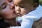 Mothers kissed baby. Close up portrait of mother kissing multiracial baby. Mother kiss child, macro. Closeup face of