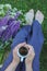 Motif of a barefoot woman sitting in a garden with wild flowers and a cup of coffee