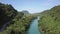 Motion along forestry banks of blue river flowing to valley