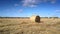 Motion around large straw bale in middle of autumn field