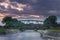 Motion blur long exposure train passing over metallic railway bridge during sunset