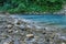 Motion blurred rapids of Khosta River with wet boulders and shore strewn with dry leaves