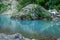 Motion blurred rapids of Khosta River with wet boulders and shore strewn with dry leaves