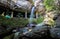 Motion blurred water and children play in  the temple under waterfall Wat Tham Heo Sin Chai waterfall. Kaeng Tana National Park,