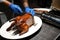 Motion of chef cutting roasted duck into a plate for customer