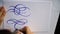 Motion video female hand writes a calligraphic flourish on sheet of paper in office