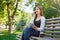 Motivated asian freelancer in the park. Girl on a bench, drinking coffee and talking on phone, while working with tablet