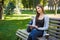 Motivated asian freelancer in the park. Girl on a bench, drinking coffee and working with tablet