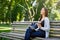 Motivated asian freelancer in the park. Girl on a bench, drinking coffee and working with tablet