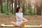 Motivated athletic positive woman in white leggins and top, practicing yoga, sitting in lotus pose and turning back, flexibility