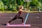 Motivated athletic woman doing sports, standing on rubber stripe training legs, exercising with rubber expander