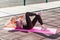 Motivated blond pretty woman in tight pants lying on mat and training outdoor summer day, doing sit ups crunch