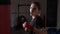 Motivated blonde female model hitting the punching bag without boxing gloves to lose weight in slow motion -