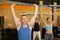 Motivated CrossFit middle-aged male athlete lifting heavy body bar or barbell during group training in gym. Functional