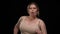 Motivated plus size sportswoman running at black background looking at camera. Portrait of inspired confident Caucasian
