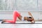 Motivated sporty woman training on mat indoor winter day, using foam roller massager for relaxation, stretching spine muscles,