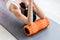 Motivated sporty woman training on mat indoor winter day, using foam roller massager for relaxation, stretching spine muscles,