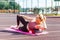 Motivated sporty woman training on mat outdoor summer day, using foam roller massager for relaxation, stretching spine