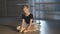 Motivated talented hard-working girl in tutu admiring beige pointes sitting on floor in ballet studio. Portrait of