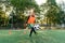 Motivated teen football player stuffs soccer ball on feet with boots. Practicing sport exercises at special stadium.