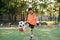 Motivated teen football player stuffs soccer ball on leg. Practicing sport exercises at artificial stadium.