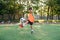 Motivated teen football player stuffs soccer ball on leg. Practicing sport exercises at artificial stadium.