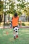 Motivated teen football player stuffs soccer ball on leg. Practicing sport exercises at artificial stadium.