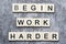 The motivating slogan Begin Work Harder formed with tile letters