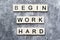 The motivating slogan Begin Work Harder formed with tile letters