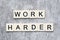 The motivating slogan Work Harder formed with tile letters
