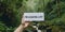 Motivational inspiring hand holding word card wanderlust in woods