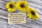 Motivational quote on torn brown paper on wooden surface with sunflowers.