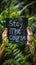 Motivational Stay The Course sign held up with two hands, promoting persistence and dedication, set against a lush green