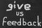 Motivational Text sign showing Give us Feedback on a chalkboard