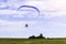 Moto paraglider flying over a field in a blue sky with clouds