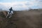 Motocross racer moves along sandy parapet turning track