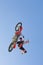 Motocross Racer Performing Stunt In Midair Against Blue Sky