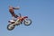 Motocross Racer Performing Stunt With Motorcycle In Midair Against Sky