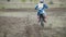 Motocross racer start riding his dirt Cross MX bike kicking up dust rear view, close up