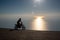 Motocrosser riding motorcycle by the sea at sunset