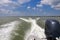 Motor boat in motion, view towards the surface of water. Blue sky with fluffy clouds