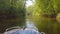 Motor boat moves along a small river or Bayou with banks overgrown with green forest or jungle