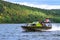 motor boat with a pirate flag sails over the reservoir on a sunny day. Small ship with tourists on board touring on reservoir